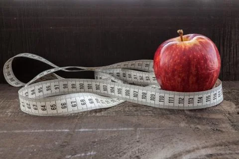 An Apple surrounded by a measuring tape tailor on wood Stock Photos