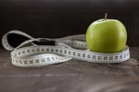 An Apple surrounded by a measuring tape tailor on wood Stock Photos