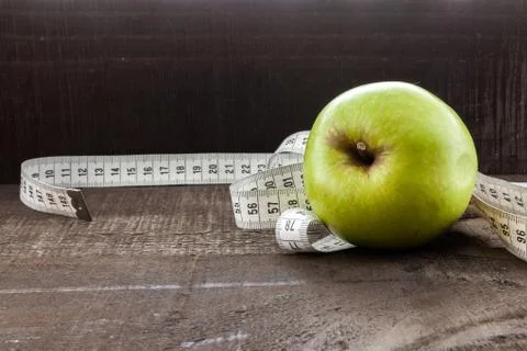 An Apple surrounded by a measuring tape tailor on wood Stock Photos
