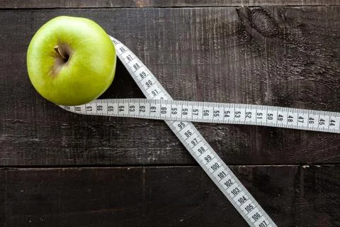 An Apple surrounded by a measuring tape tailor on wood Stock Photos