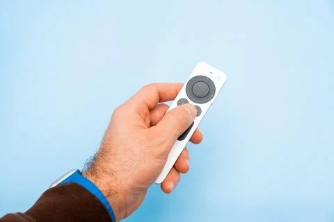 Apple TV 4k Remote controller in mans hand on the blue background Stock Photos