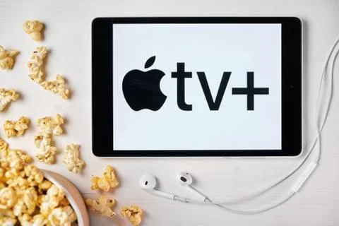 Apple tv plus logo on the screen of the tablet laying on the white table and Stock Photos