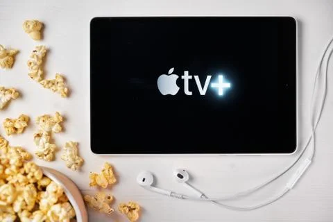 Apple tv plus logo on the screen of the tablet laying on the white table and Stockfoto's