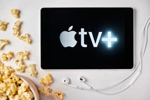 Apple tv plus logo on the screen of the tablet laying on the white table and Stockfoto's