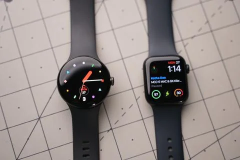 An apple Watch and a Google Pixel Watch on top of a table Stock Photos