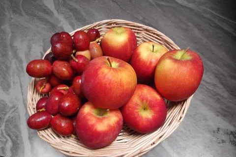 Apples and dark red dates in a basket. Stock Photos
