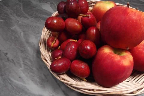 Apples and dark red dates in a basket. Stock Photos