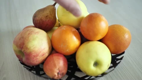 Apples and oranges in a bowl on the table man takes Stock Footage 151286579