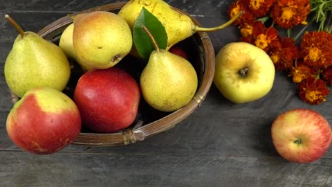 Apples and pears in a wicker basket, marigold flowers are on a wooden board Vídeo Stock 317054239