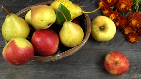 Apples and pears in a wicker basket, marigold flowers are on a wooden board Vídeo Stock 317054250