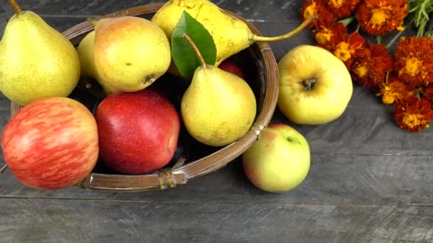 Apples and pears in a wicker basket, marigold flowers are on a wooden board Vídeo Stock 317054256