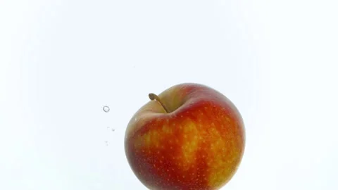Apples are thrown into a container with water on an isolated background Stock Footage 148458244
