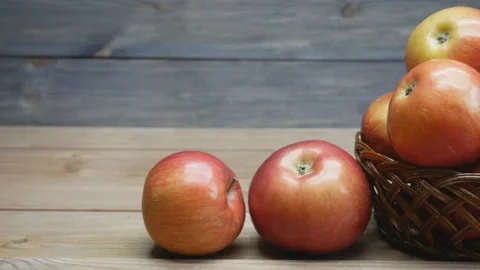 Apples in a basket on a wooden table. Camera slowly moves from left to right. Stock Footage 106725031
