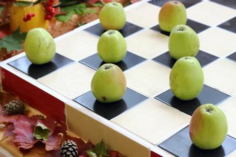 Apples on chessboard Stock Photos