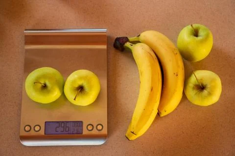 Apples on a digital kitchen scale and beside are bananas and apples Stock Photos