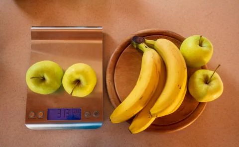 Apples on a digital kitchen scale and beside are bananas and apples Stock Photos
