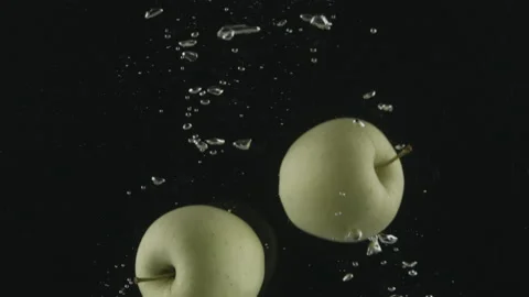 Apples falling into water in slow motion on black background. Stock Footage 171543607