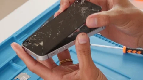 Apple's iPhone SE with completely broken screen being opened for repair Stock Footage 106260713
