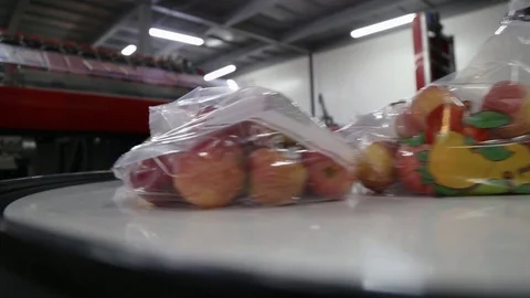Apples packed in a plastic bag move along the conveyor. Stockbeeldmateriaal 125662886