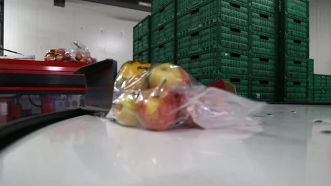 Apples packed in a plastic bag move along the conveyor. Stockbeeldmateriaal 125663174