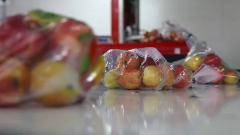 Apples packed in a plastic bag move along the conveyor. Stockbeeldmateriaal 125663363