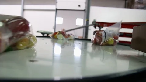 Apples packed in a plastic bag move along the conveyor. Stockbeeldmateriaal 125664080