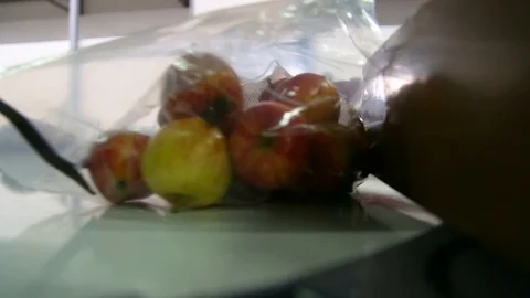 Apples packed in a plastic bag move along the conveyor. Stockbeeldmateriaal 125664200