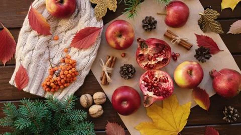 Apples, pomegranate, cones, walnuts, fallen leaves on a wooden background Stock Photos