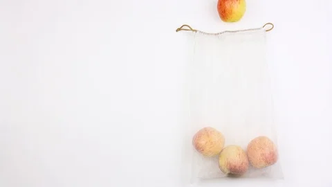 Apples sequentially one by one come out from reusable recycled mesh grocery bag Stockbeeldmateriaal 111211103