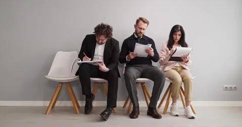 Applicants seated in lobby completing forms on clipboards recruitment interview Stock Footage 341800137