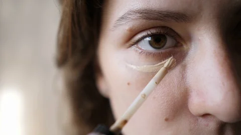 Application of concealer under the female eye close-up. A caucasian girl is Stock Footage 120721688