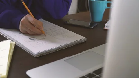 The application developer draws sketches in a notebook. Works remotely from home Video stock 88170572