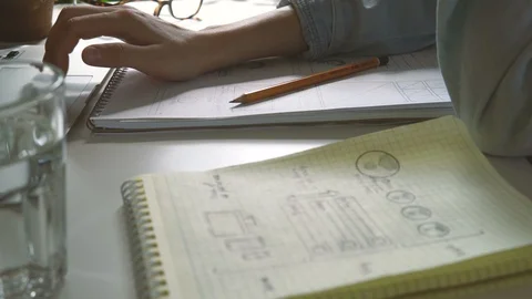 The application developer draws sketches in a notebook. Works remotely from home Stock Footage 88172272