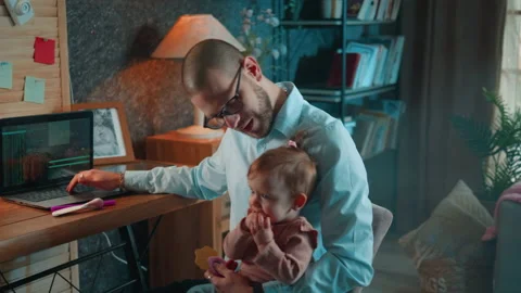 Application developer is working on his laptop and care of his baby Stock Footage 230224516