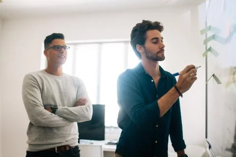 Application developer writing on board in office Stock Photos