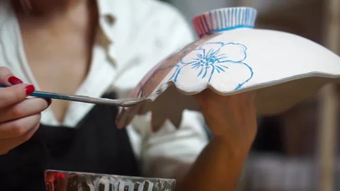 Application of glaze with a brush to a painted piece of pottery in a workshop 库存影片 257259847