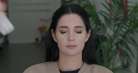 Application of makeup setting spray by a makeup artist on a clients face. Video stock 323241422