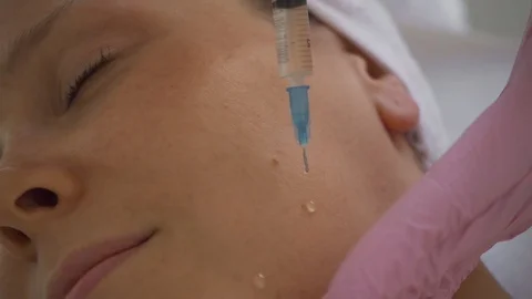 Application of oil on face. Girl does anti-aging facial skin massage in a luxury Stock Footage 120577675