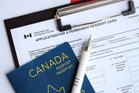 Application for permanent resident card on table with pen and canadian passport Stock Photos