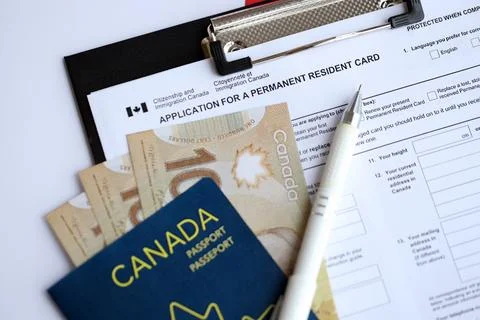 Application for permanent resident card on table with pen and canadian passport Stock Photos