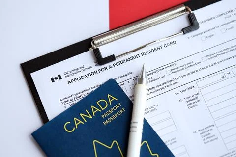 Application for permanent resident card on table with pen and canadian passport Stock Photos