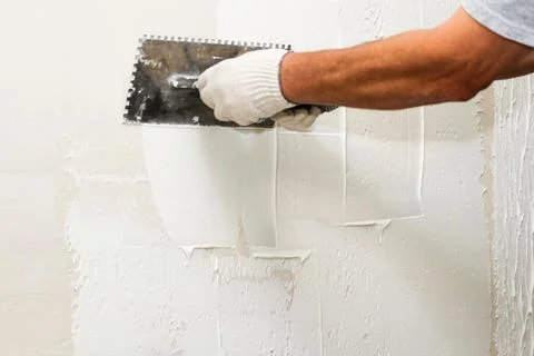 Application of plaster on the wall with a comb. Stock Photos