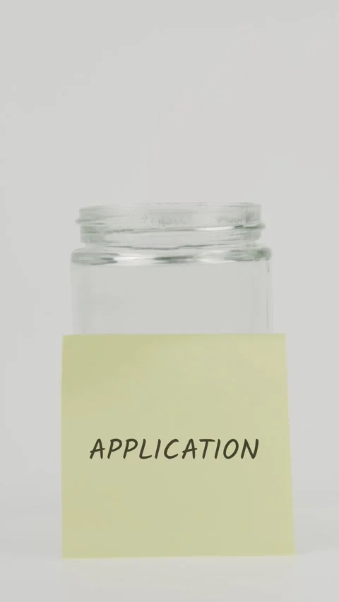 Application text or word on yellow sticky note attached to glass jar Stock Footage 311677541