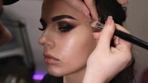 Application of the tonal base with a professional brush on the face of the girl Stock Footage 84988330