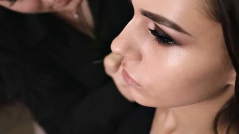 Application of the tonal base with a professional brush on the face of the girl Stock Footage 84988349