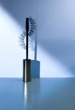 Applicator mascara and false eyelashes with drop shadow on blue background. Stock Photos