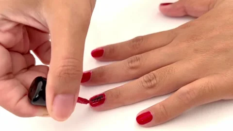Apply a glossy red glitter top coat on gently painted red nails Stock Footage 260723127