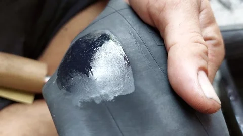 Apply glue and wait for it to dry before preparing to patch the tire. Stock Footage 293273317