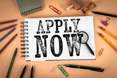 Apply Now Message on Notebook Page With Magnifying Glass and Office Supplies Foto stock