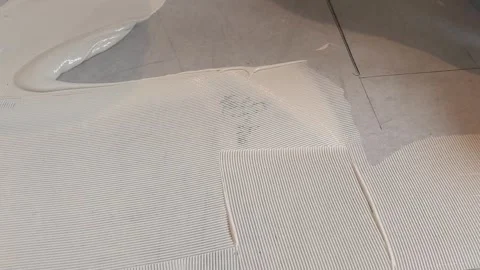 Applying adhesive to floor for tile installation in home renovation project Stock Footage 325176478